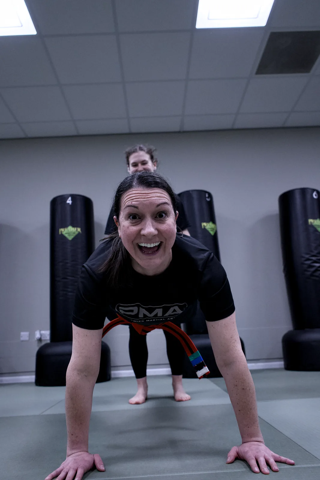 An adult student grinning at the camera mid press-up